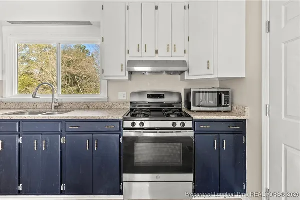 a kitchen with granite countertop white cabinets and appliances