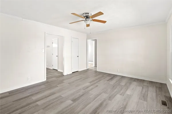 a view of an empty room with a window and wooden floor