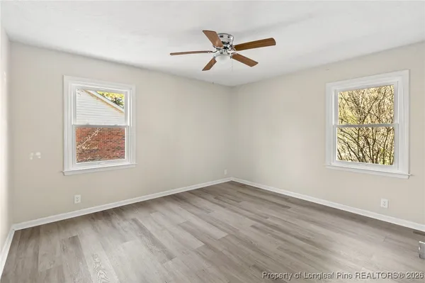 an empty room with wooden floor and ceiling fan