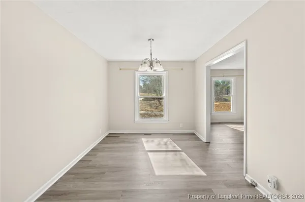 an empty room with kitchen chandelier and windows