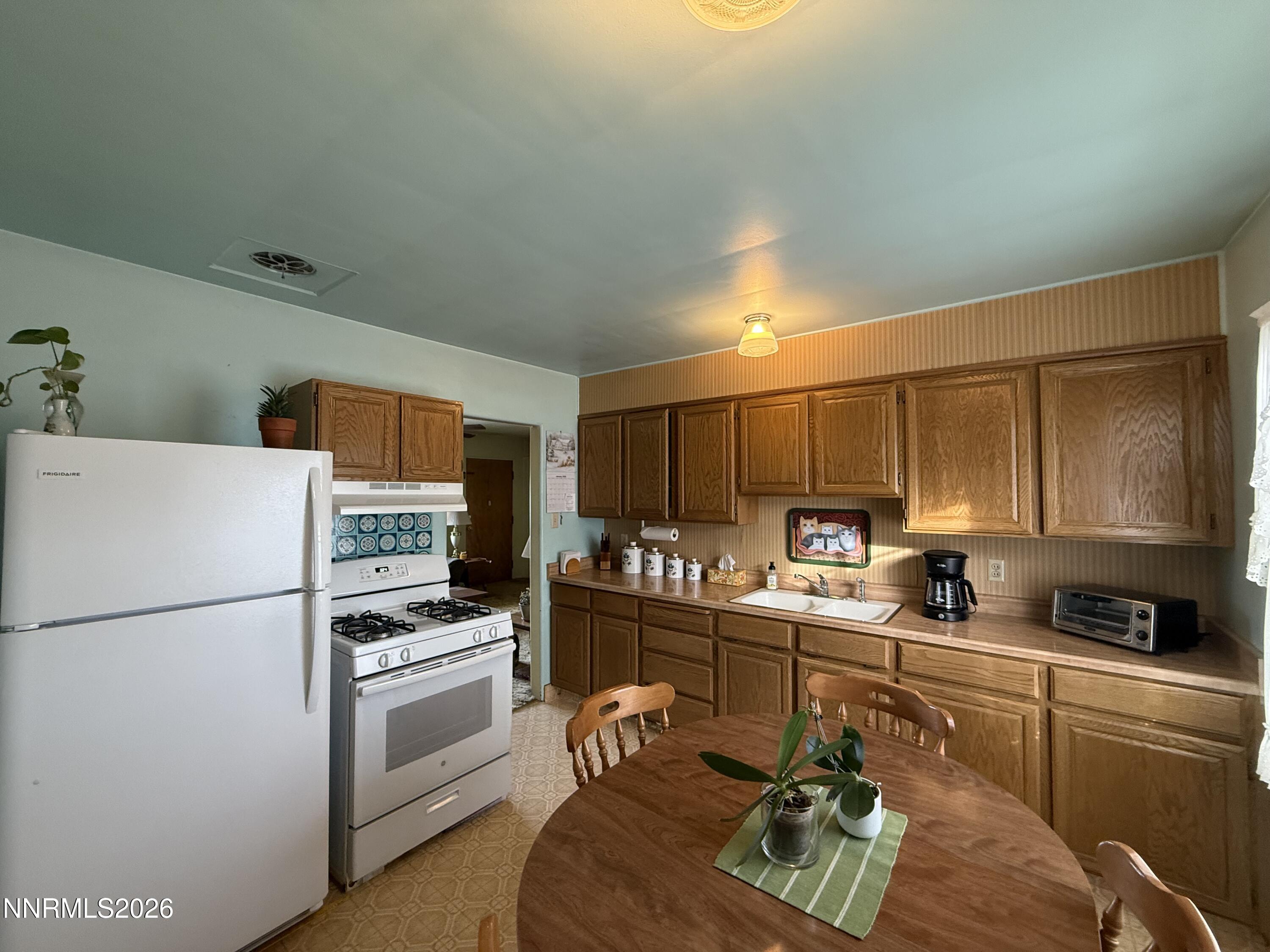 870 Capitol Hill Avenue Reno, NV 89502 - Photo 2 of 24 a kitchen with a refrigerator a stove a sink dishwasher and white cabinets with wooden floor