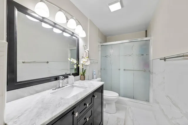 a bathroom with a granite countertop sink a toilet and shower