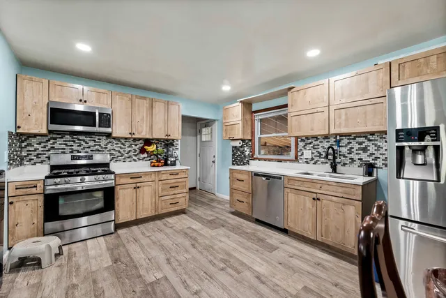 a kitchen with stainless steel appliances white cabinets a sink a stove a refrigerator and microwave