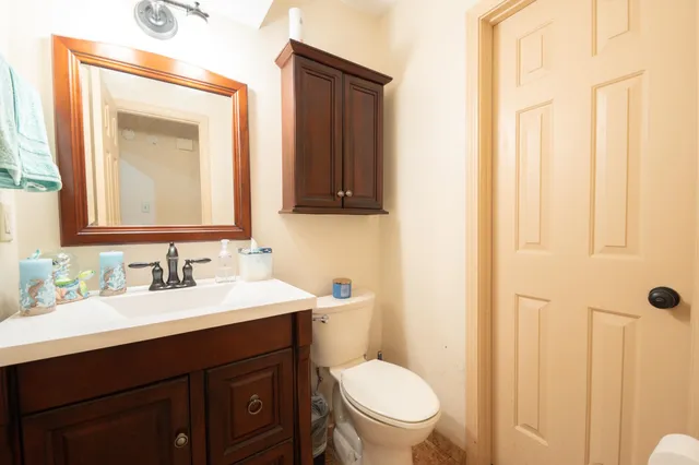 a bathroom with a toilet a sink a mirror a vanity and a window