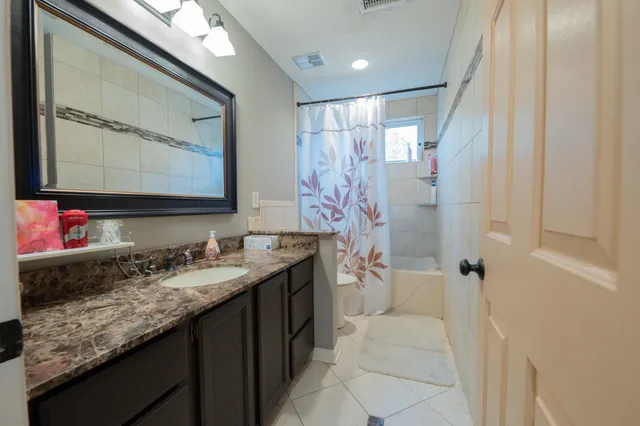a bathroom with a granite countertop sink a mirror and shower