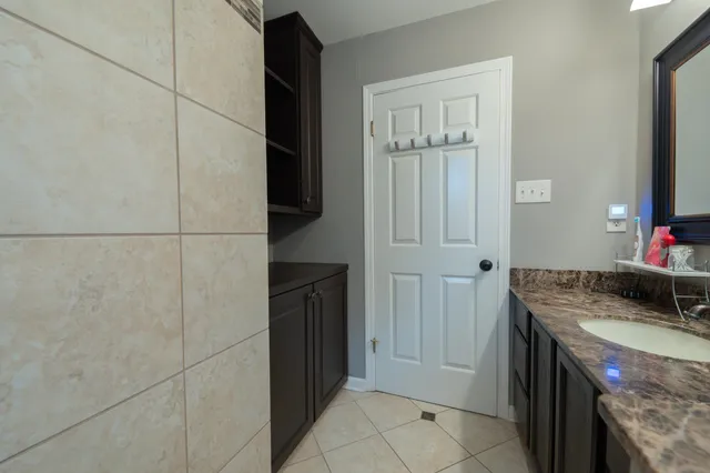 a bathroom with a granite countertop sink and a washing machine