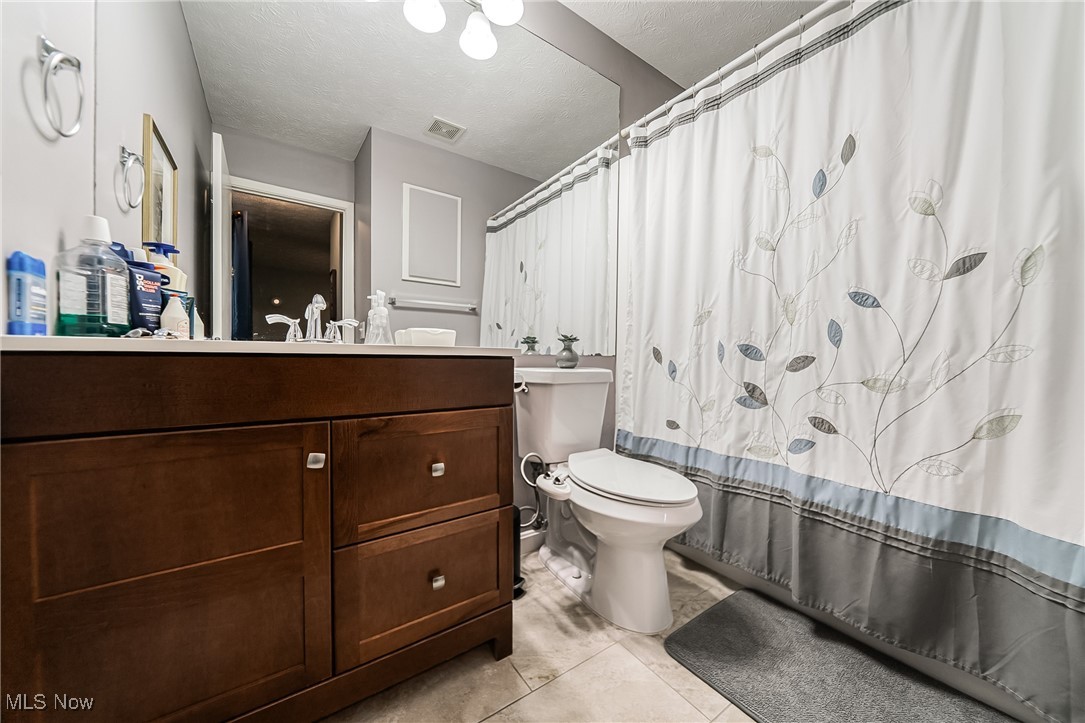10794 Waterfall Road Strongsville, OH 44149 - Photo 19 of 37 Full bathroom featuring vanity, a textured ceiling, and light tile patterned floors