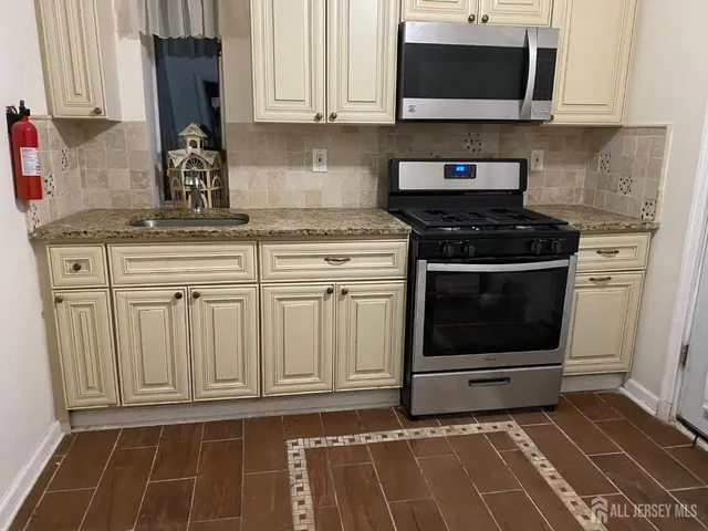 a kitchen with granite countertop a stove top oven microwave and cabinets
