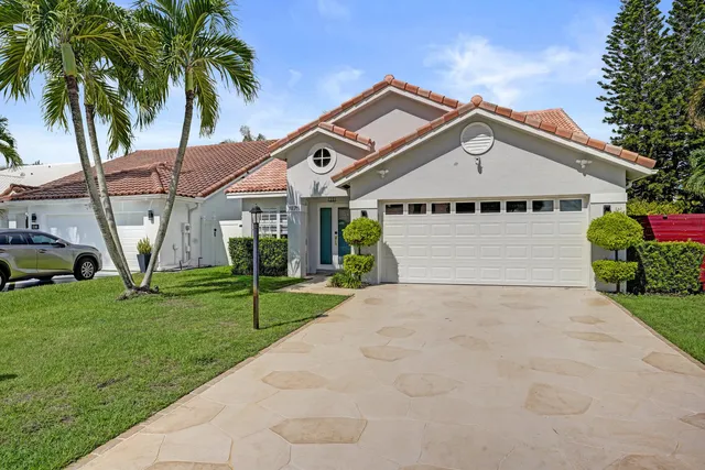 a view of a big house with a big yard and palm trees
