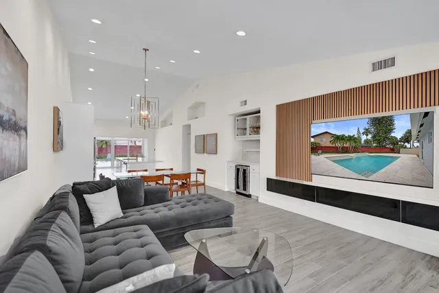 a view of an empty room and kitchen with wooden floor