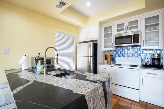 a kitchen with granite countertop a sink a stove and refrigerator
