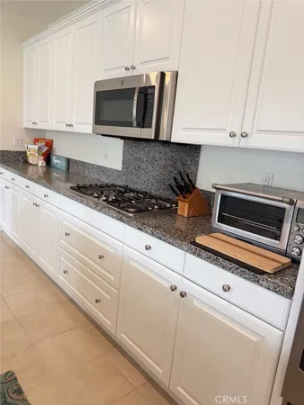 a kitchen with granite countertop white cabinets and stainless steel appliances