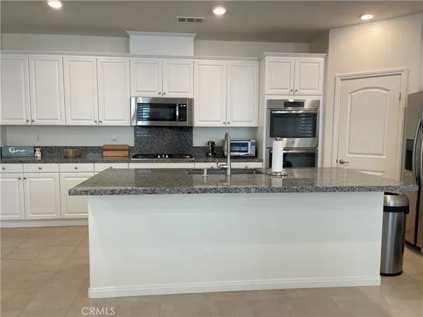 a kitchen with granite countertop white cabinets and stainless steel appliances