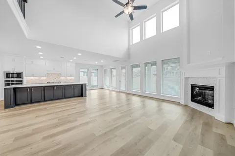 a view of an empty room with wooden floor and a kitchen