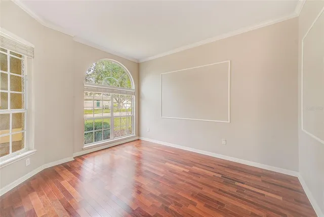 a view of an empty room with wooden floor and a window