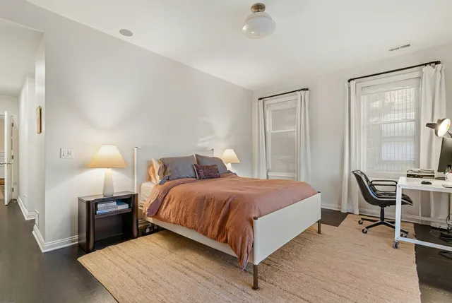 a bedroom with a bed a chair and a potted plant on the table