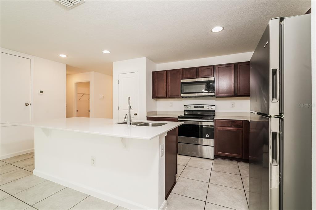 1473 Lucerne Loop Road Northeast Winter Haven, FL 33881 - Photo 8 of 25 a kitchen with granite countertop a refrigerator and a stove top oven