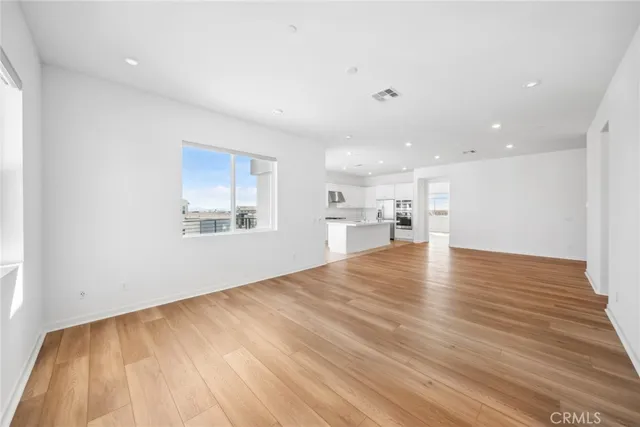 a view of empty room with wooden floor and window