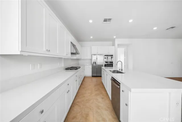 a large kitchen with stainless steel appliances granite countertop a lot of counter space and wooden floors