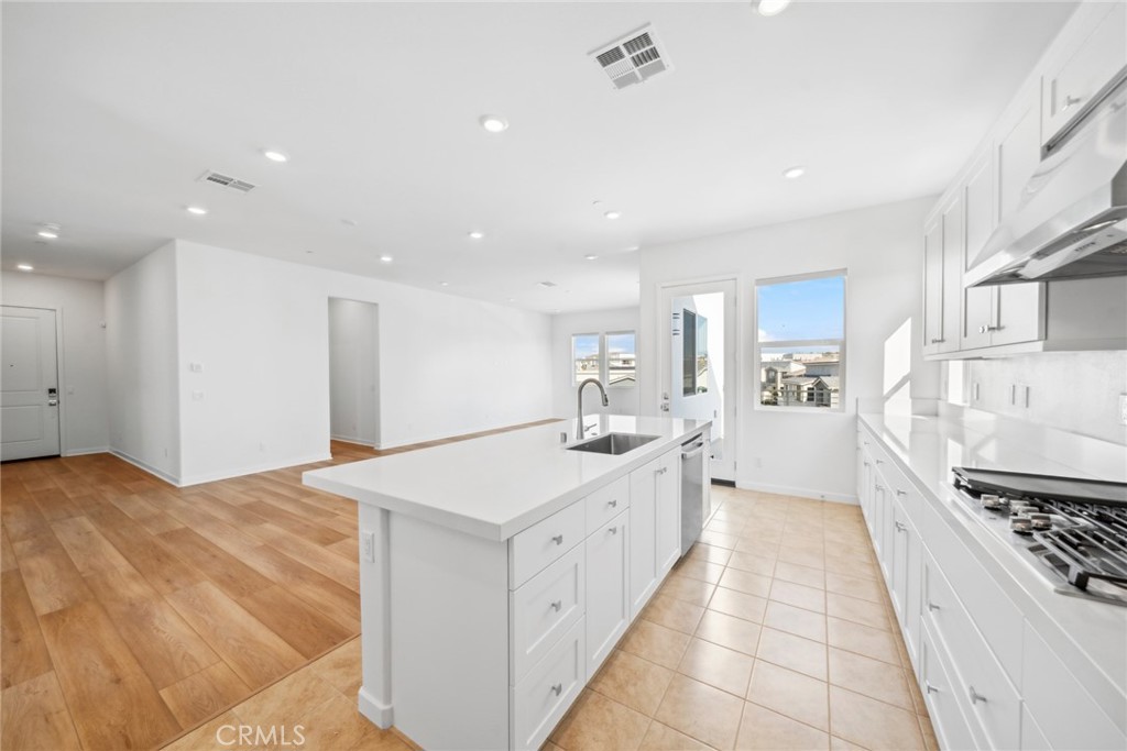 111 Baluster Irvine, CA 92618 - Photo 9 of 30 a large white kitchen with stainless steel appliances a stove a chimney a sink and cabinets