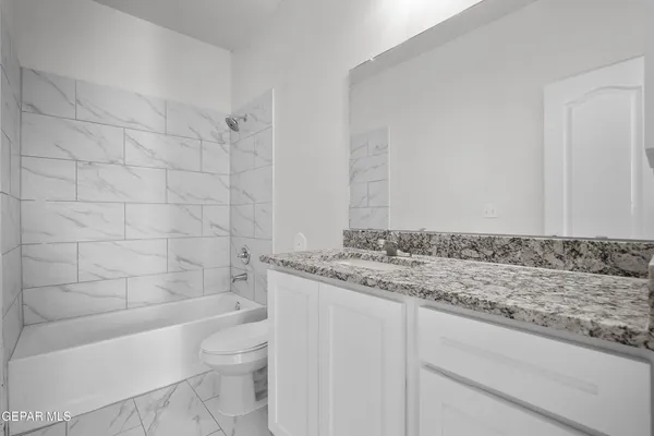 a bathroom with a granite countertop toilet a sink and bathtub