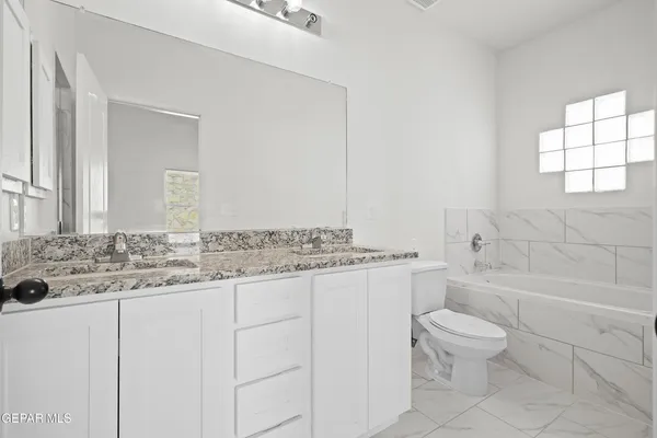 a bathroom with a granite countertop sink a toilet a mirror and bathtub