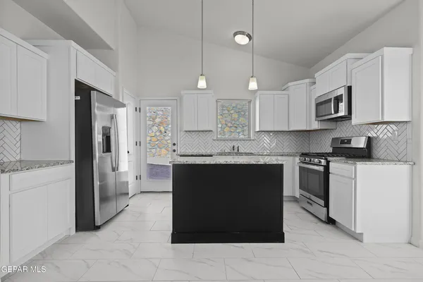 a kitchen with stainless steel appliances granite countertop a refrigerator and a stove top oven