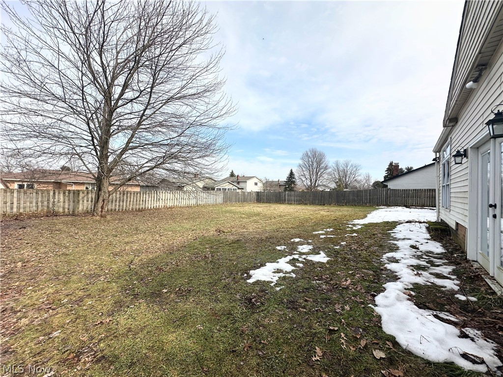 Snowy yard featuring a fenced backyard