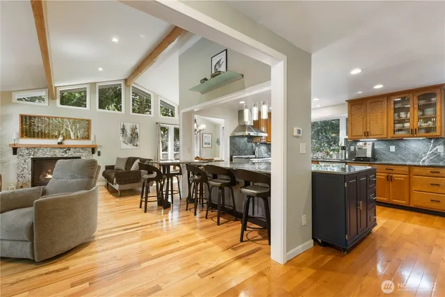 a living room with couches and kitchen view with wooden floor