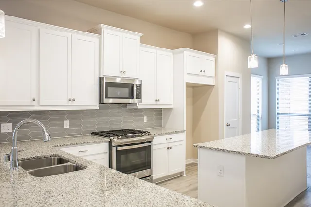 a kitchen with granite countertop a sink stove and refrigerator