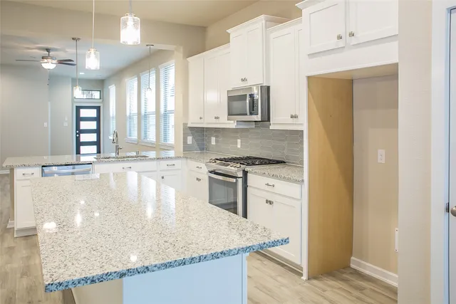 a kitchen with stainless steel appliances granite countertop a sink a stove and a refrigerator