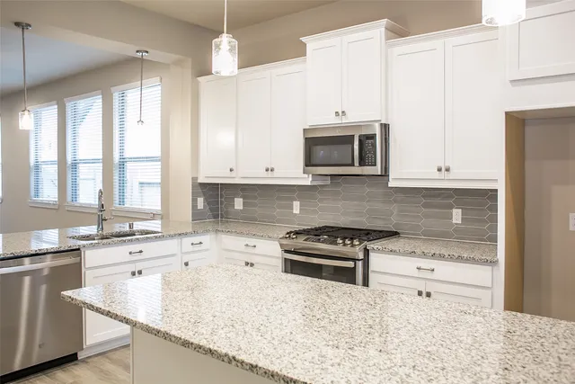 a kitchen with stainless steel appliances granite countertop a sink stove and microwave