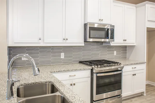 a kitchen with granite countertop white cabinets and stainless steel appliances