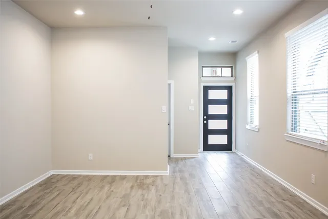 an empty room with wooden floor and windows