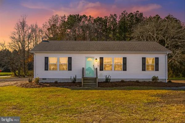 a front view of house with yard and trees in the background