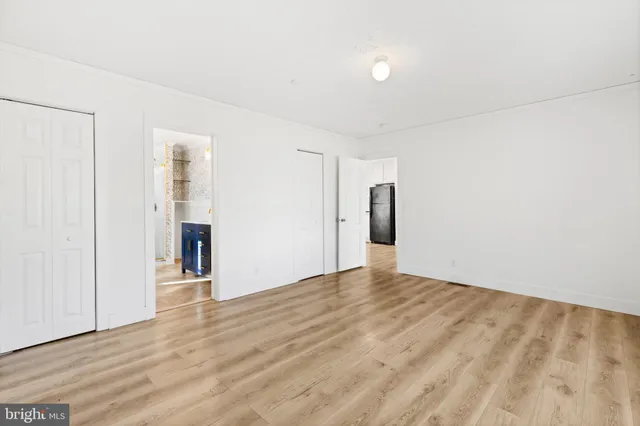 a view of an empty room with wooden floor and closet