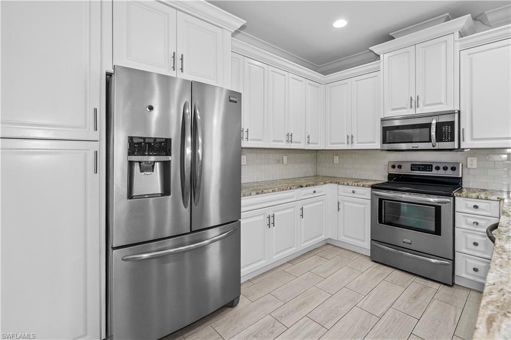183 7th Street Naples, FL 34113 - Photo 13 of 50 a kitchen with stainless steel appliances granite countertop a refrigerator stove a sink and microwave