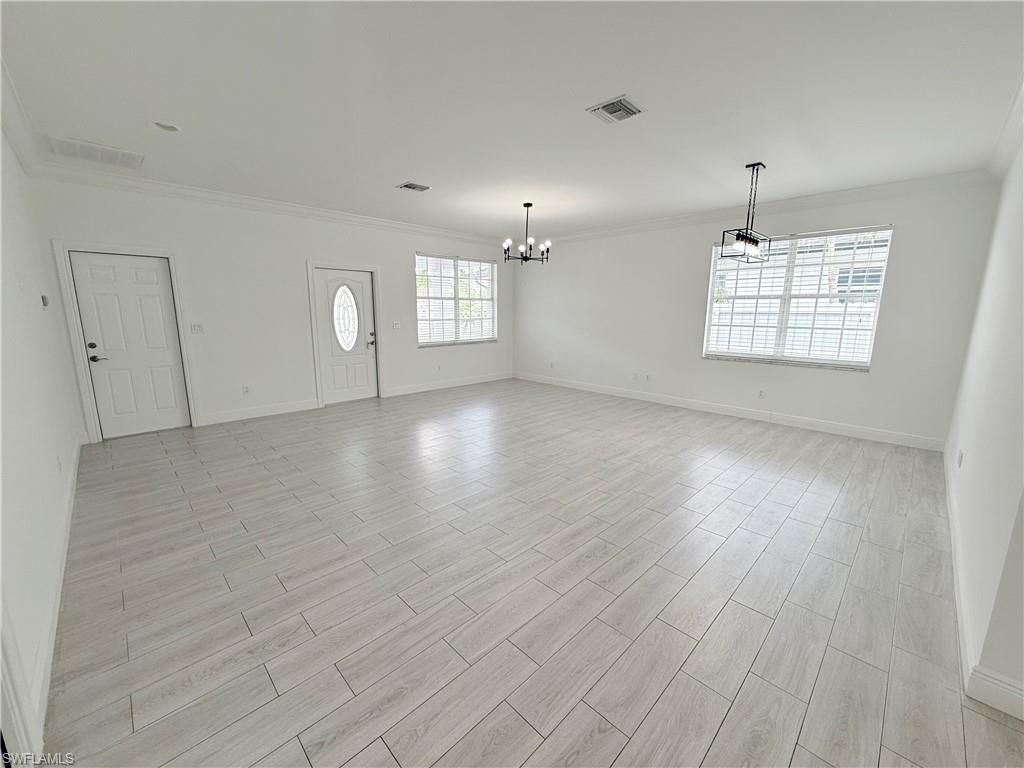 183 7th Street Naples, FL 34113 - Photo 6 of 50 an empty room with wooden floor chandelier and windows