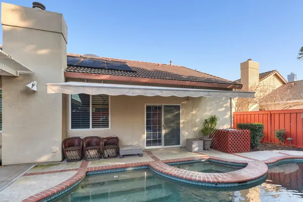 a view of a swimming pool with a patio and a backyard