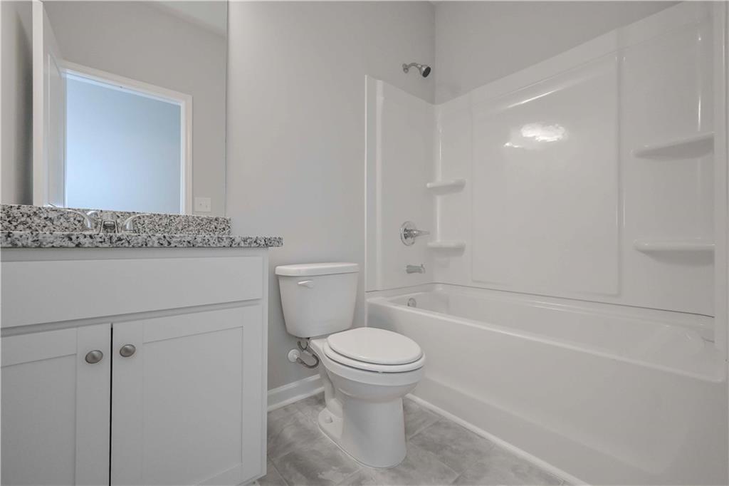 506 Charleston Place Villa Rica, GA 30180 - Photo 21 of 25 a bathroom with a granite countertop toilet a sink and a bathtub