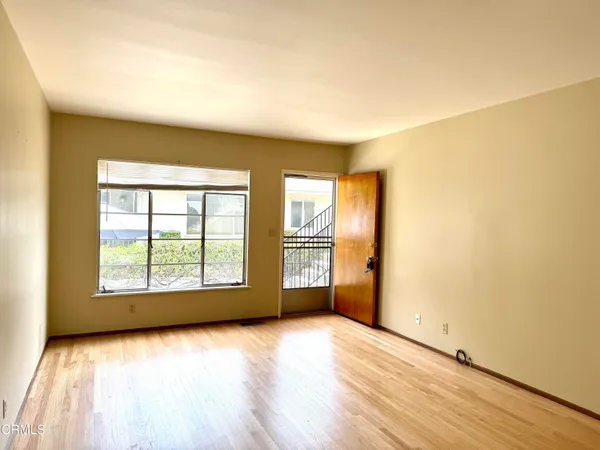 an empty room with wooden floor and windows
