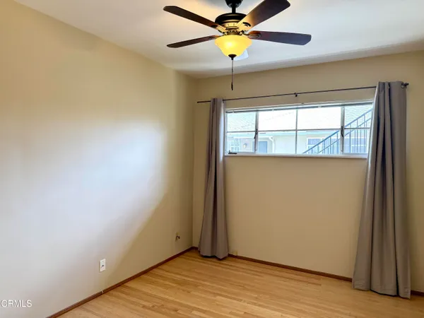 an empty room with wooden floor fan and windows