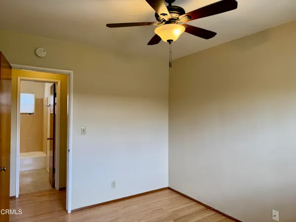 a view of a room with wooden floor a ceiling fan and a bathroom