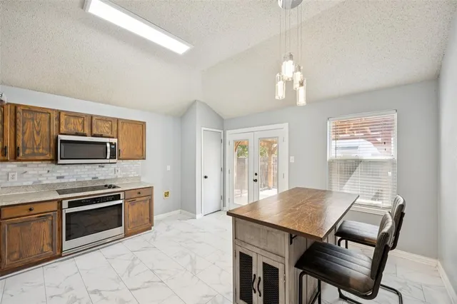 a open kitchen with stainless steel appliances granite countertop a stove refrigerator and microwave