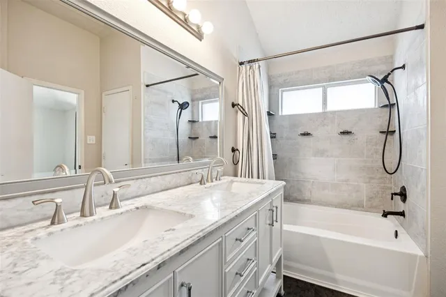 a bathroom with a granite countertop bathtub shower sink vanity and mirror