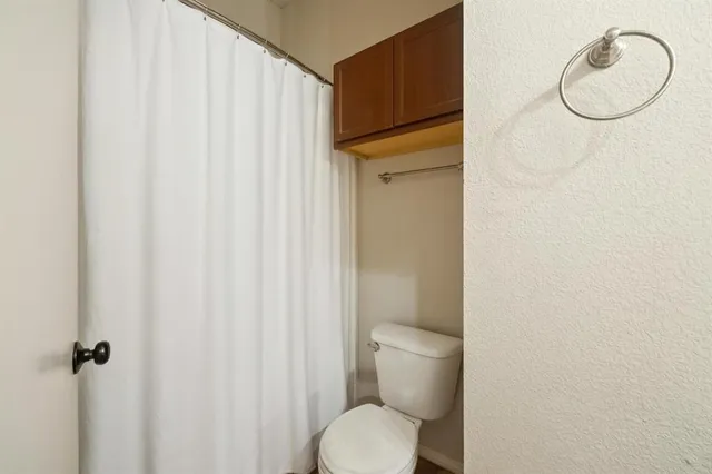 a bathroom with a toilet and a shower curtain