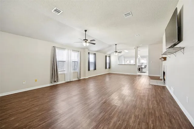 a view of a livingroom with wooden floor and a kitchen