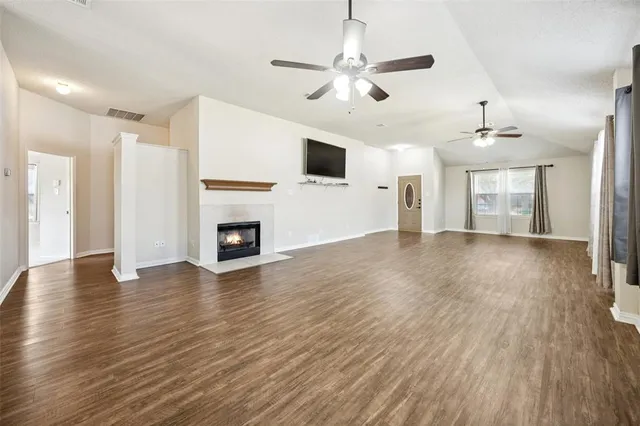 an empty room with wooden floor fireplace and windows