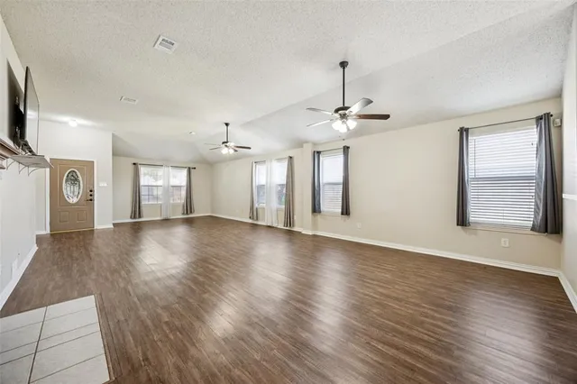 a view of an empty room with window and wooden floor