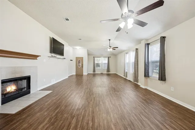 a view of an empty room with wooden floor fireplace and a window
